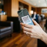 一只女性的手持iPhone，屏幕二维码，商务模糊背景