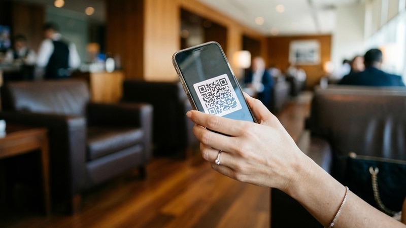 一只女性的手持iPhone，屏幕二维码，商务模糊背景